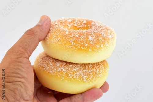 Two delicious yellow donuts are in the hand of the customer on a white background. 