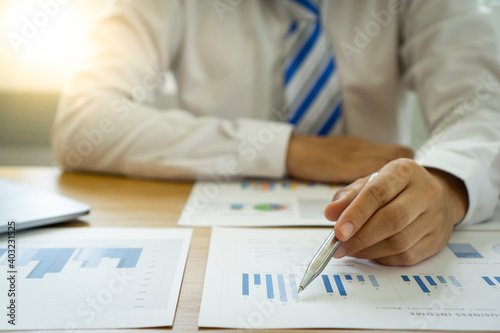 Obraz na plátně Asian male finance staff holding a pen and pointing at the graph document