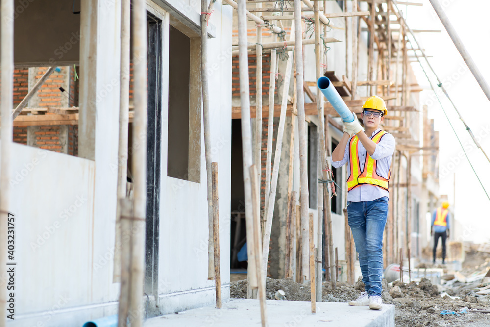 Asian man construction worker holding pipe and working on site.