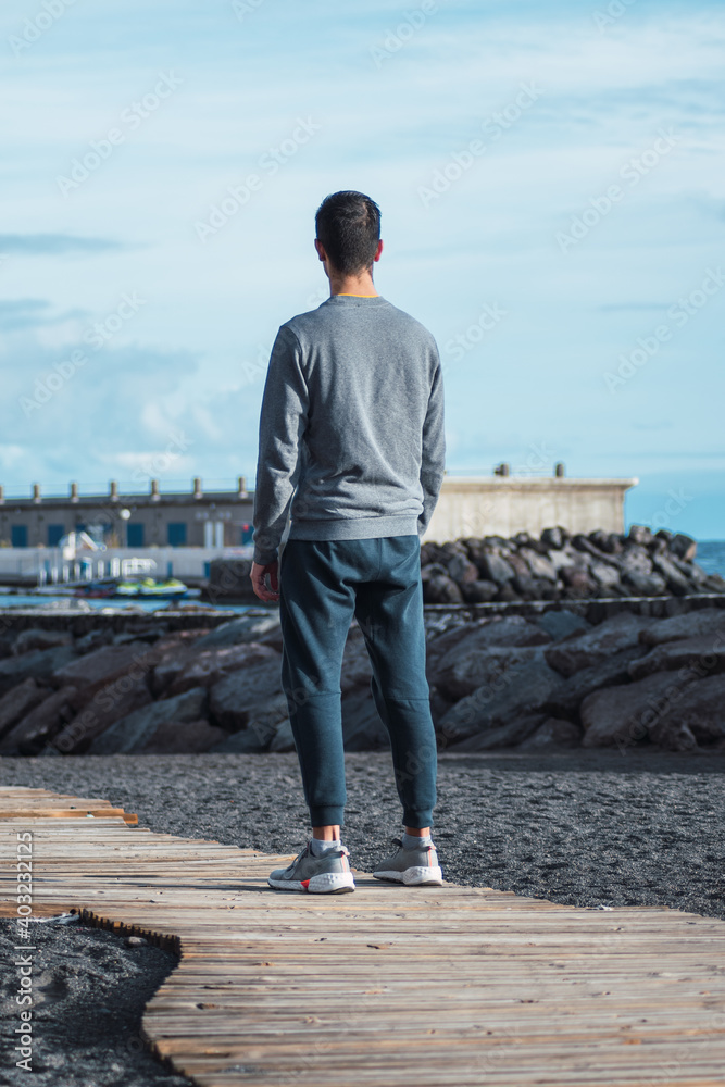 Man from behind looking at a pier