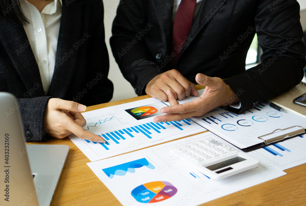 Asian businesswoman or accountant working pointing graph discussion and analysis data charts and graphs and using a calculator to calculate numbers.Business finances and accounting concept Asian businesswoman or accountant working pointing graph discussion and analysis data charts and graphs and using a calculator to calculate numbers.Business finances and accounting concept