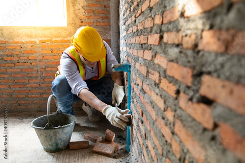 Fototapeta Man bricklayer installing bricks on construction site