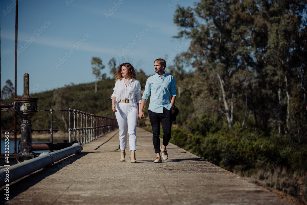 A couple of lovers walking hand in hand with a beautiful view in spring. White clothes she, the young man in blue. Newly married.
