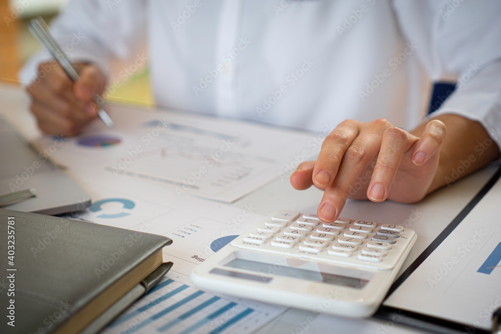 Fototapeta premium The female finance staff is calculating the company's profits from the graph on the home office desk. Concept finance