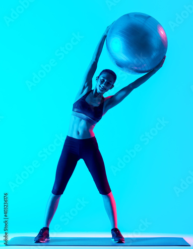 one mixed races woman exercsing fitness pilates exercices isolated on blue blackground