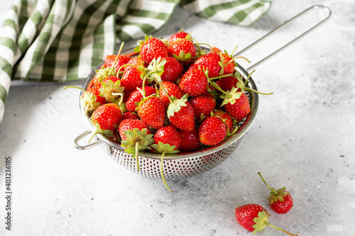 Strawberry. Strawberries in a metal bowl on a light gray background. Lots of strawberries. Top view with copyspace photo