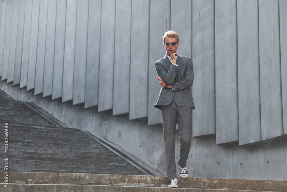 Posing for a camera. Young businessman in grey formal wear is outdoors in the city Posing for a camera. Young businessman in grey formal wear is outdoors in the city