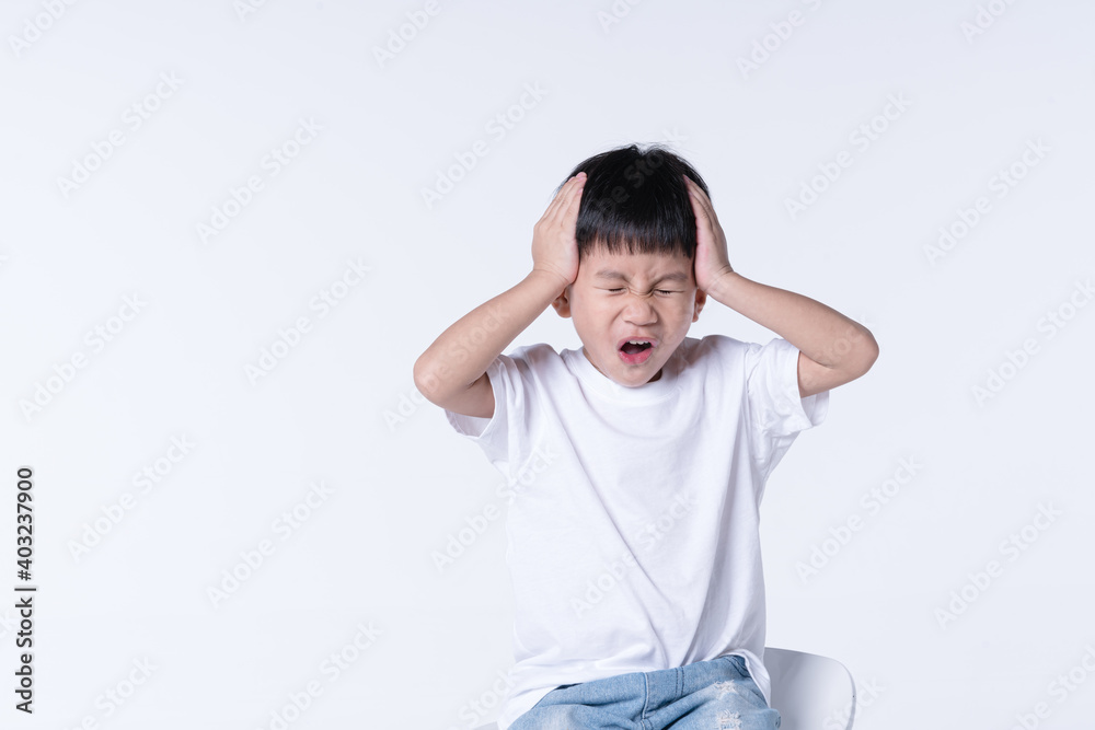 Asian boy touching his head with hurt expression Asian boy touching his head with hurt expression