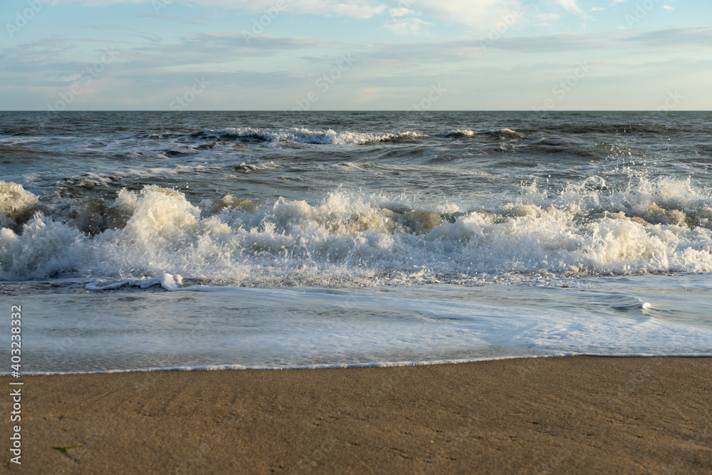 Sandy coast with waves and blue sky