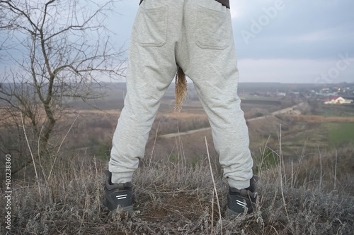 A man stands on the edge of a high hill and looks into the valley where the houses are located