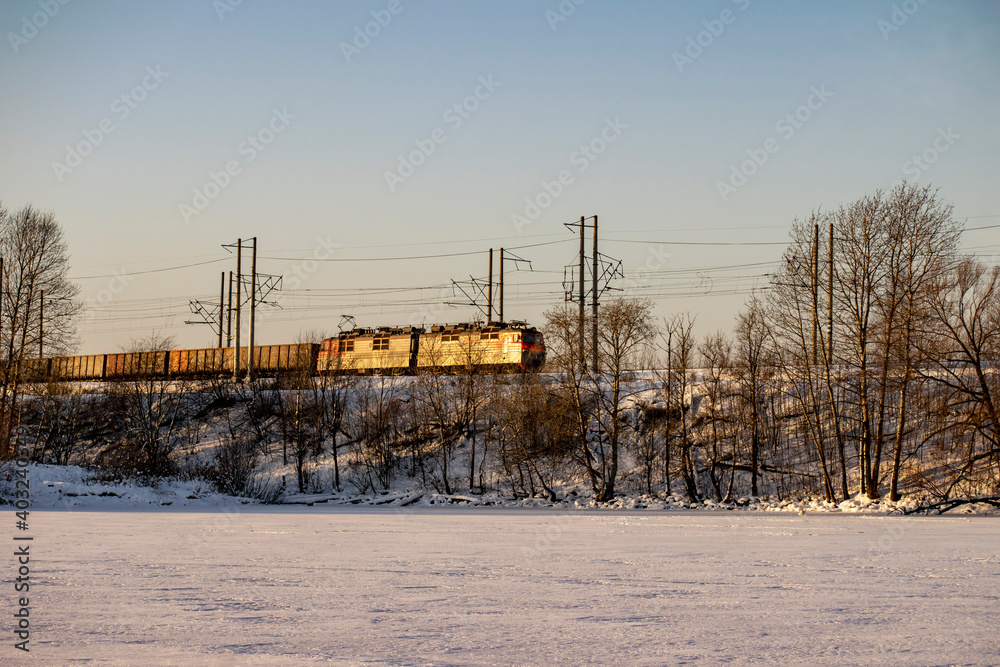 A railway locomotive rushes along a snow-covered mountain.
