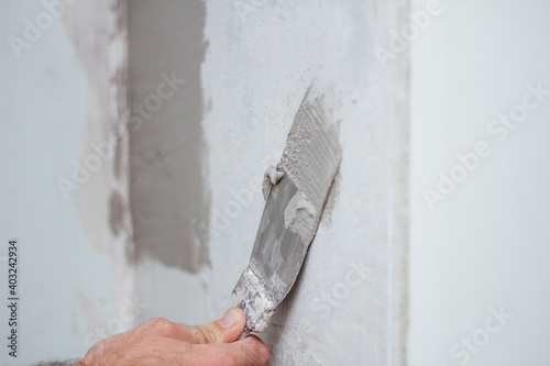 man hand with trowel plastering a wall, skim coating plaster walls.