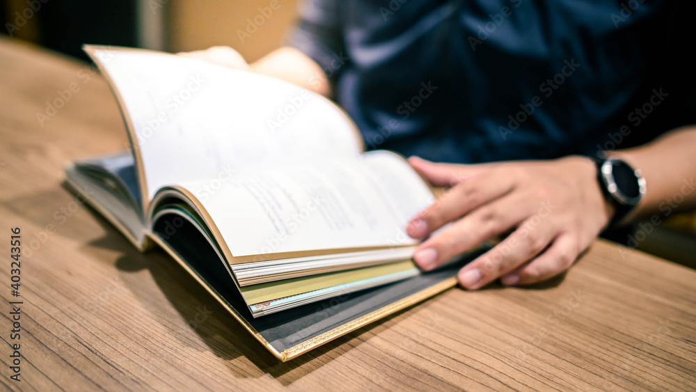 Male university student reading book in college library. Self learning and leisure activity. Education concept
