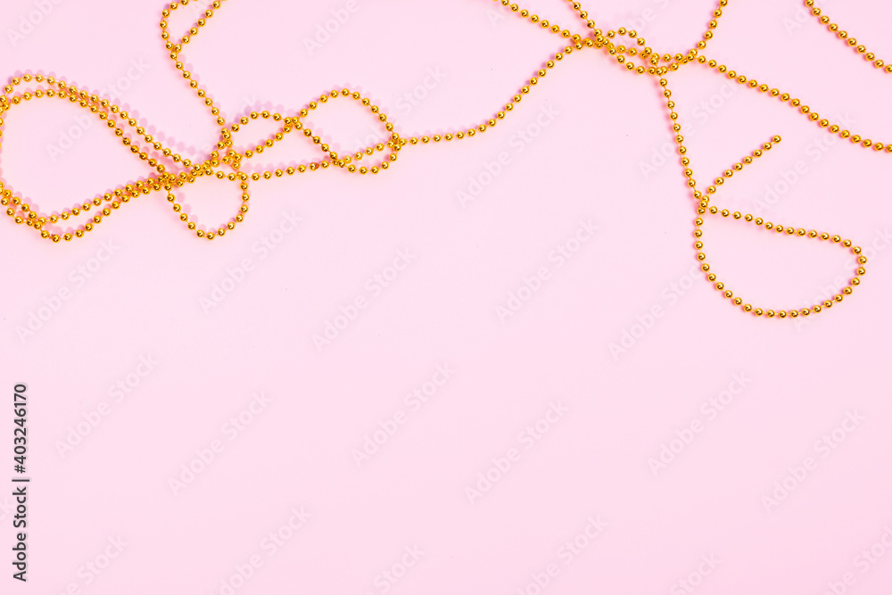 Valentine's Day or birthday concept. Golden beads on a pink background. Top view. Valentine's Day or birthday concept. Golden beads on a pink background. Top view.