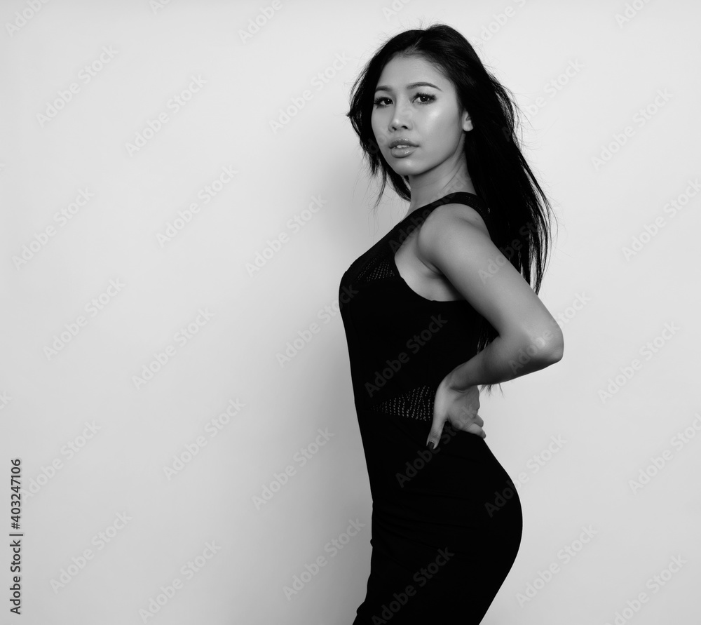 Naklejka premium Beautiful asian woman with long black hair posing in dress on grey background