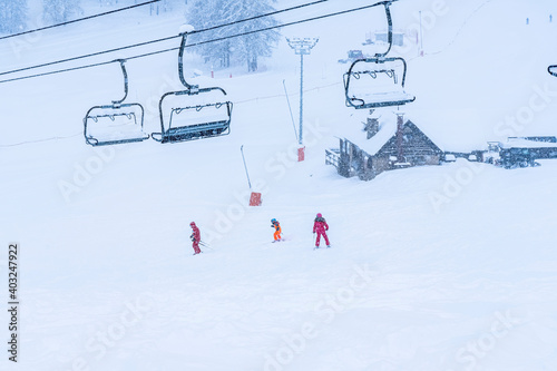 Auron, France 01.01.2021 Snowing on the ski slopes. Empty chair ski lift. Scenic landscape. Children skiers ride in the snow background. Hight quality photo