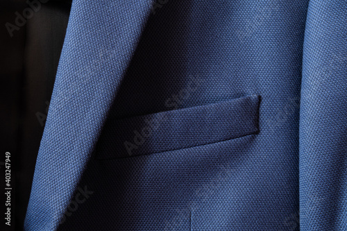 High resolution with details and quality shot of formal dark blue wool suit fabric texture. with front pocket decoration under light and shadow ambient. Ideal for background or wallpaper.