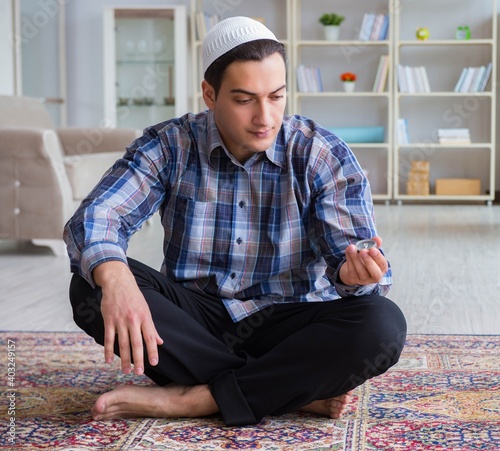 Young muslim man praying at home photo