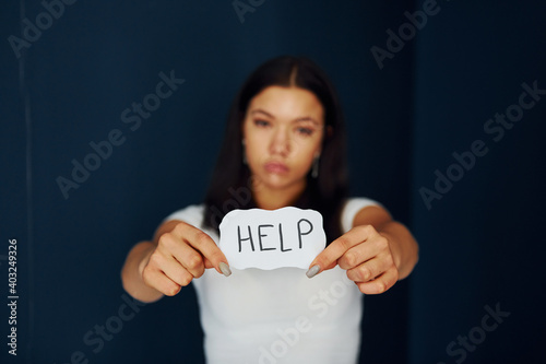 Young scared woman holds sign and ask for help. Conception of domestic violence