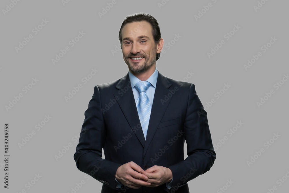 Portrait of happy businessman on gray background. Attractive man in business suit looking at camera with a smile. Portrait of happy businessman on gray background. Attractive man in business suit looking at camera with a smile.