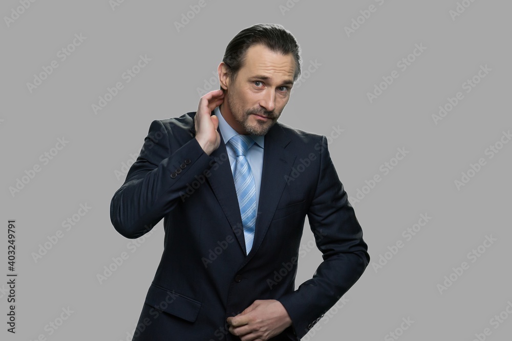 Handsome caucasian businessman preens before camera. Charismatic caucasian businessman is preening standing against gray background. Handsome caucasian businessman preens before camera. Charismatic caucasian businessman is preening standing against gray background.