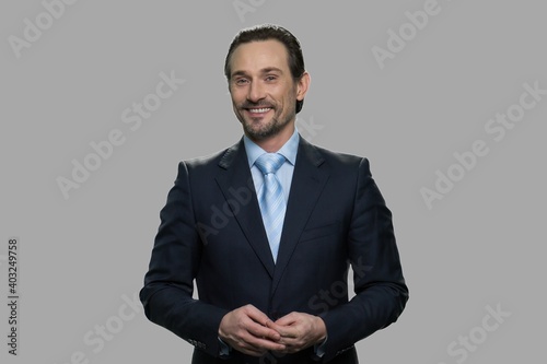 Portrait of happy businessman on gray background. Attractive man in business suit looking at camera with a smile.