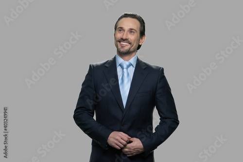 Happy smiling businessman daydreaming on gray background. Portrait of happy thoughtful businessman looking up.