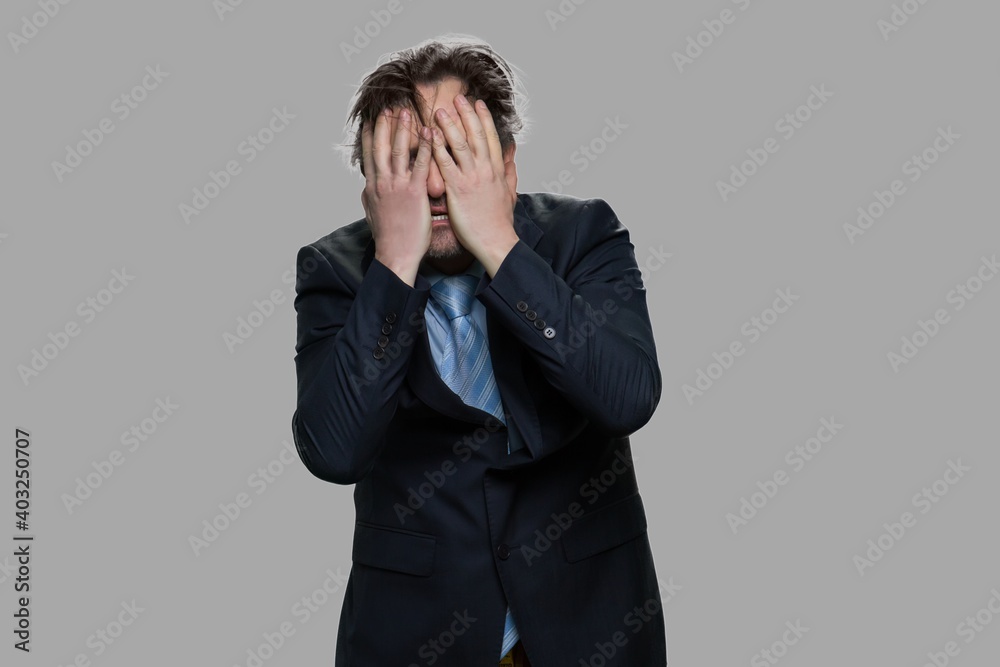 Mature businessman in despair covers his face. Financial problems, recession or bankruptcy concept. Mature businessman in despair covers his face. Financial problems, recession or bankruptcy concept.