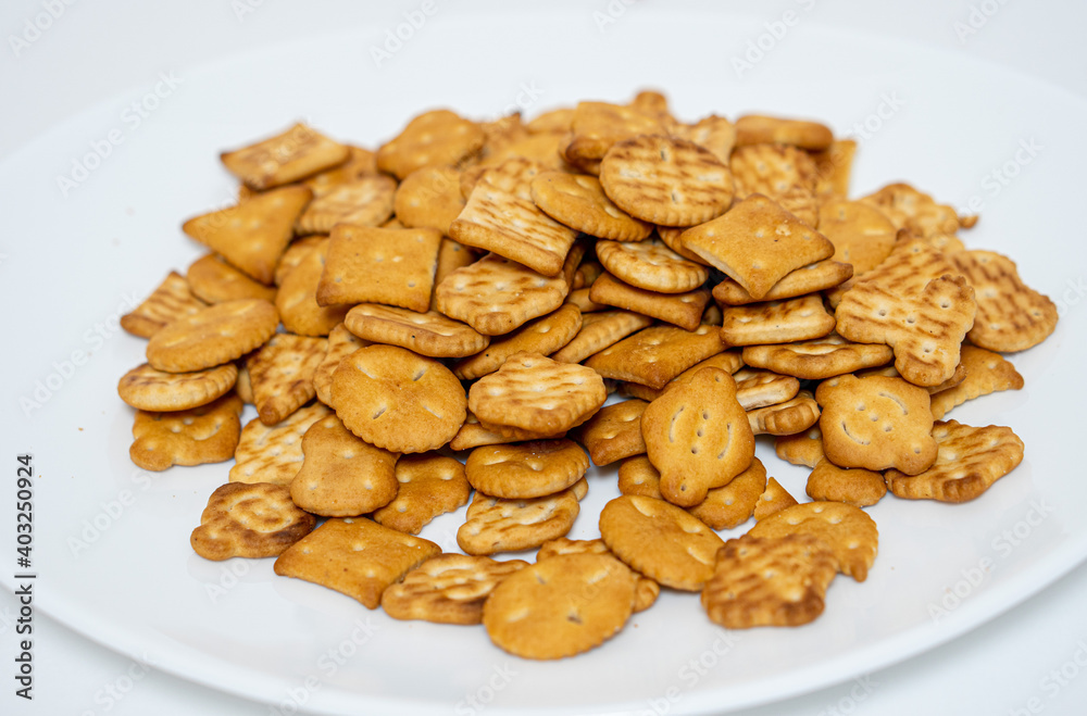 Salty biscuit cracker on a white plate on a white background Salty biscuit cracker on a white plate on a white background