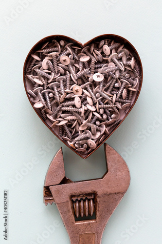 The heart full of metal screws with a fixing wrench. Male gift for Valentine's day