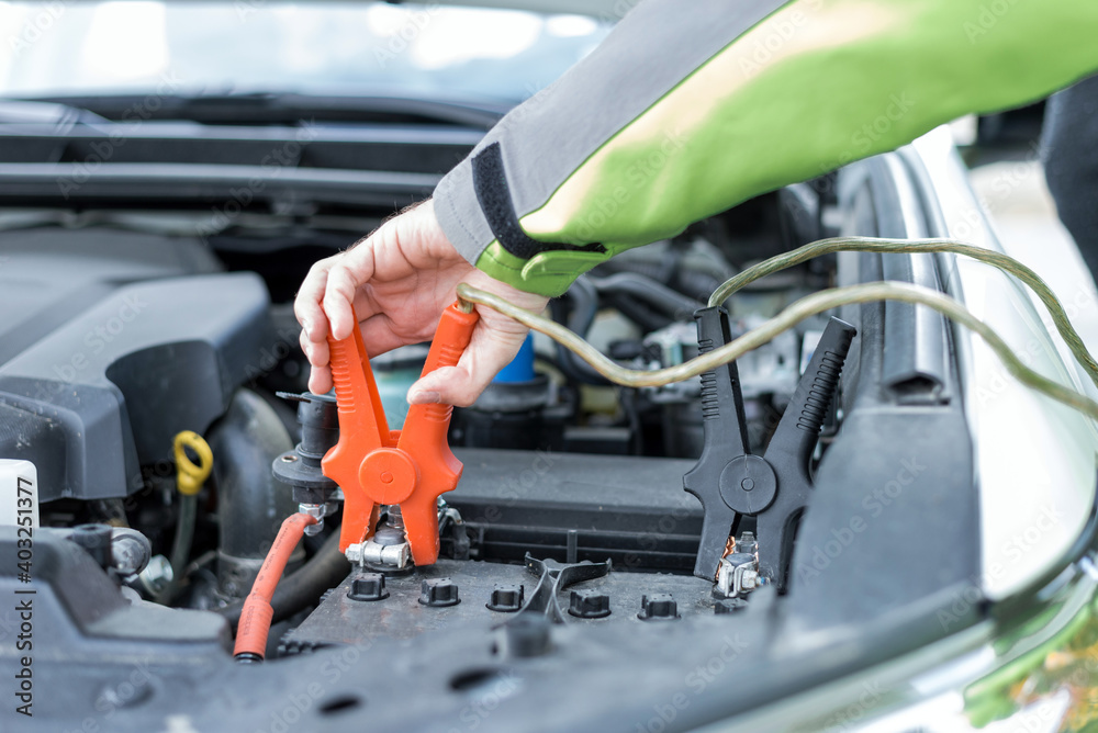 Hand putting pliers on the battery to start a car engine. Hand putting pliers on the battery to start a car engine.