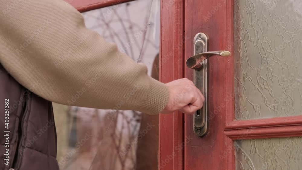 a man opening the security door of the house by turning a key in the lock.
