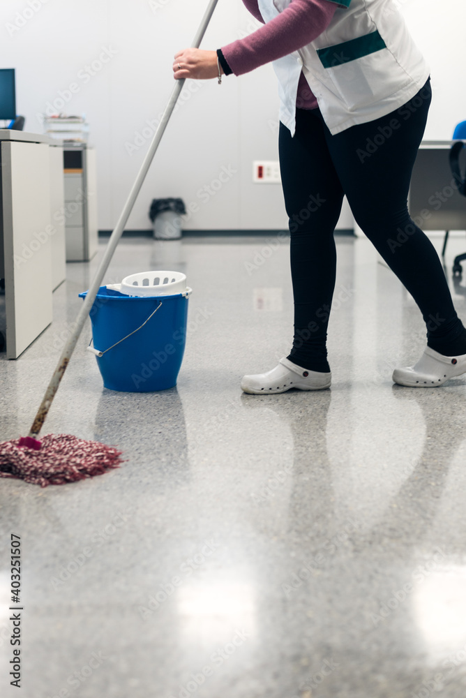 Fototapeta premium Woman cleaning school classroom with bucket and mop. Disinfection of covid-19, coronavirus.