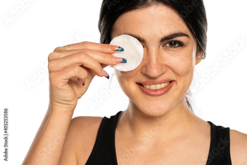 beautiful young freckled woman cleaning her face with a cotton pad