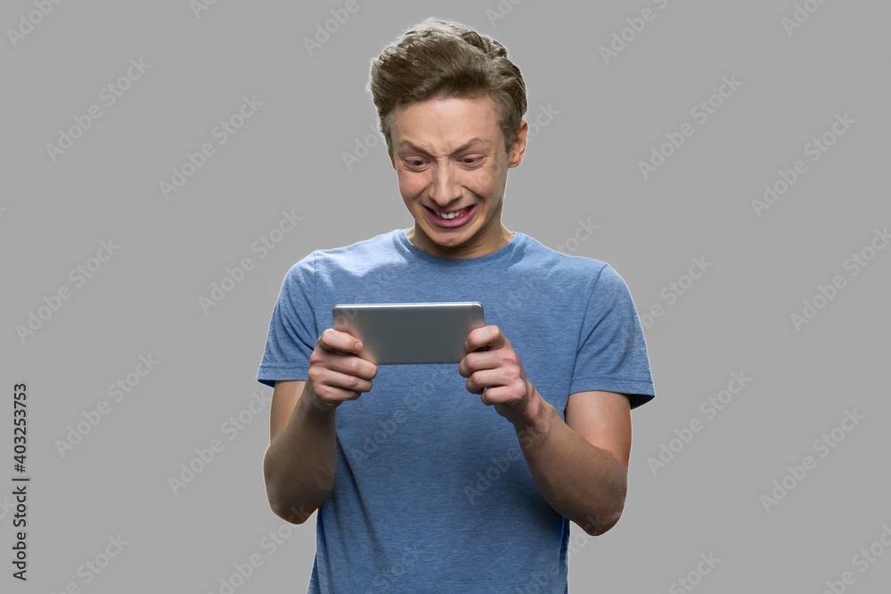 Teen boy playing online game. Funny teenage guy playing video game on his smartphone, front view. Addiction of electronic gadget.