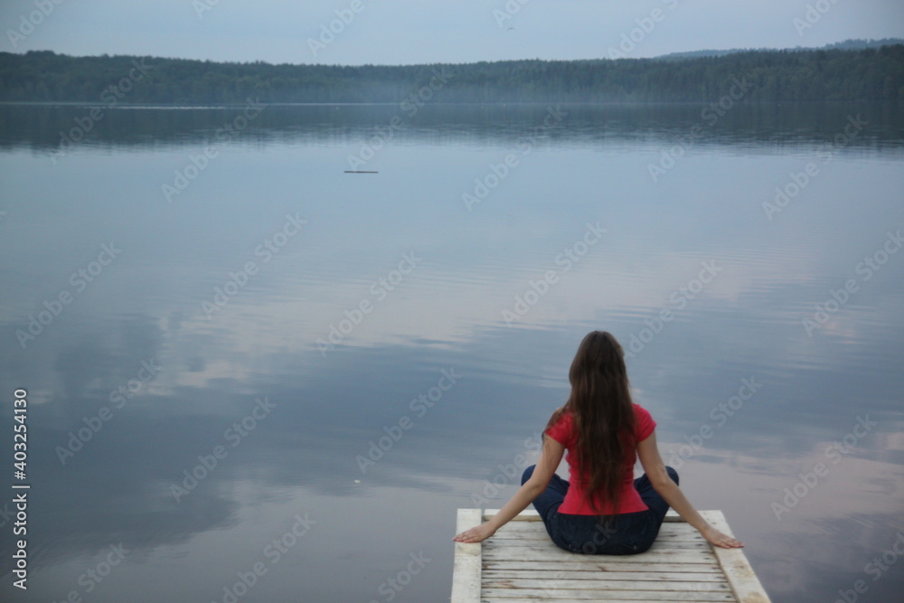 A young woman with long hair rests on a coast of a lake