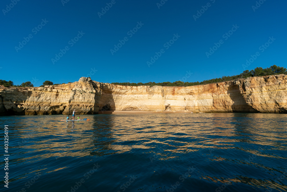 father and twho young children paddle on a SUP board along the Algarve coast in Portugal