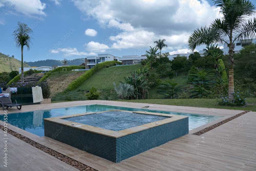 Las frescas aguas azules de la piscina en medioo de un ambiente campestre y tropical con vegetacion de la region cafetera de Colombia. Eje cafetero Colombiano. Patrimonio cultural cafetero.