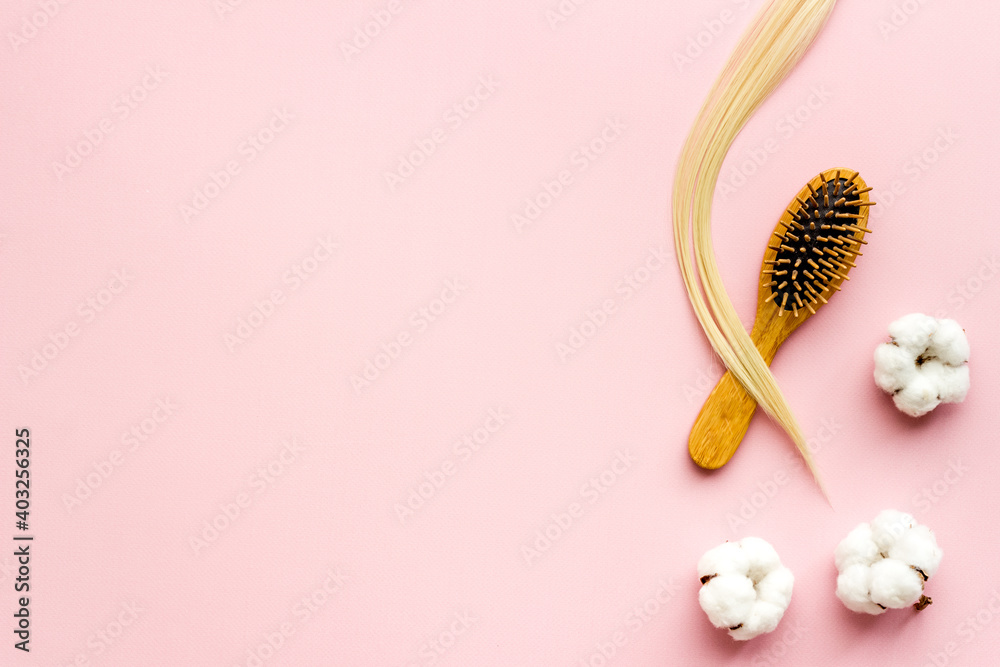 Curl of blond hair with bamboo comb and herbs. Top view flat lay