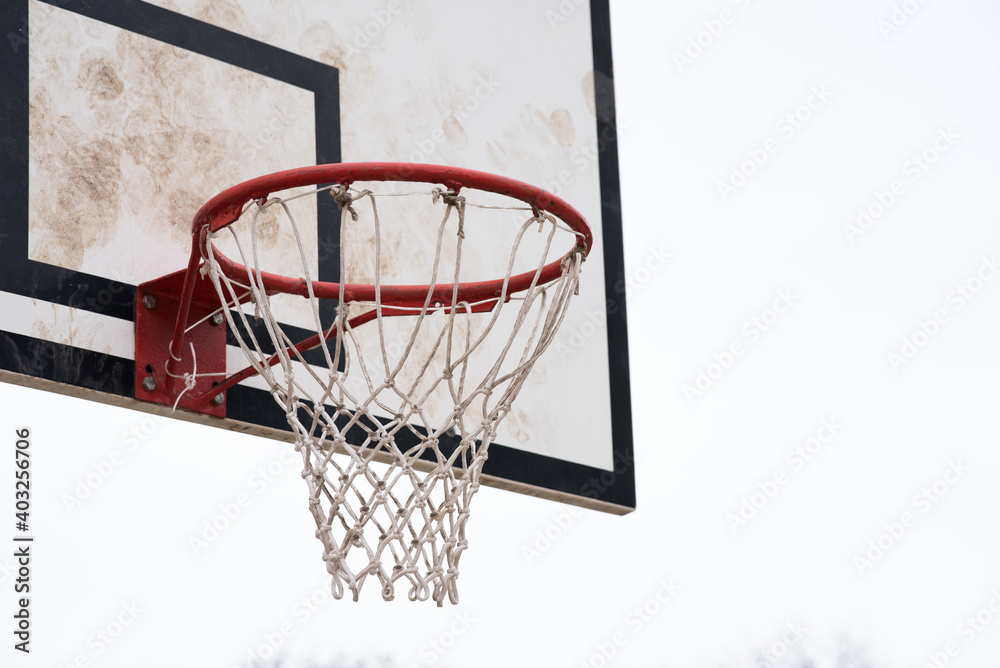 Basketball hoop, basket with white net and white blown up sky in background