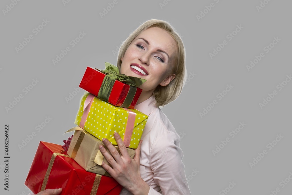 Happy woman with gift boxes on gray background. Beautiful smiling woman received many gifts for Birthday. End of the year bonus. Happy woman with gift boxes on gray background. Beautiful smiling woman received many gifts for Birthday. End of the year bonus.