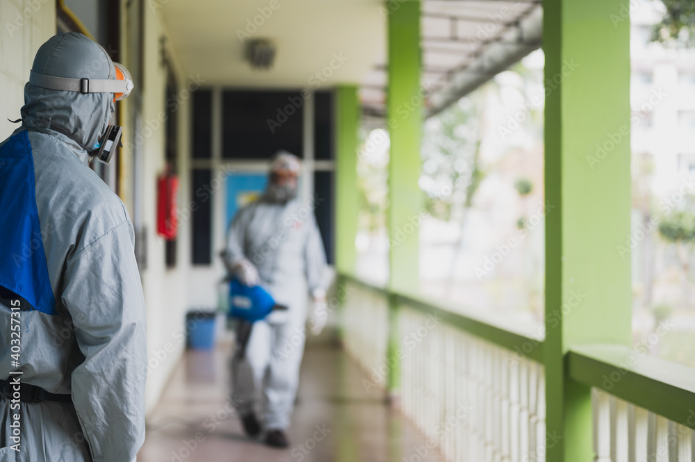 Disinfecting of office to prevent COVID-19, person in white hazmat suit with disinfect in office, coronavirus healthcare system concept Disinfecting of office to prevent COVID-19, person in white hazmat suit with disinfect in office, coronavirus healthcare system concept