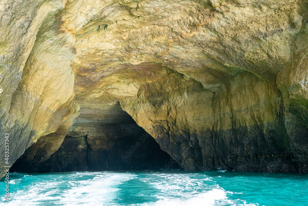 view from inside a cave on the ocean coast with turquoise water and sunny blue sky outside