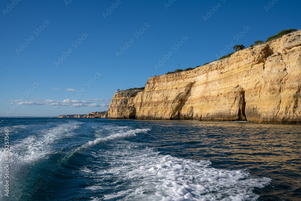 wake of a high speed motorboat and view of ocean with cliffs