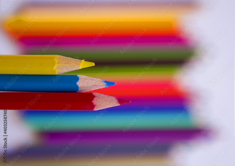 Beautiful colored pencils on a blurred background of multicolored wooden colors. Beautiful colored pencils on a blurred background of multicolored wooden colors.