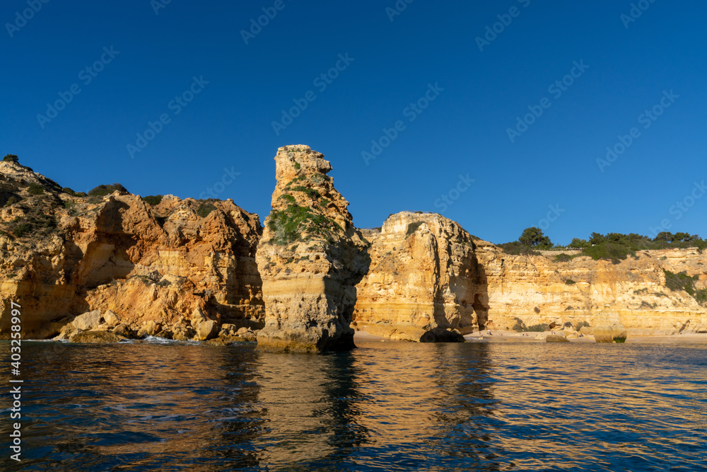 the beaches and cliifs of the Algarve Coast in Portugal under bright blue sky