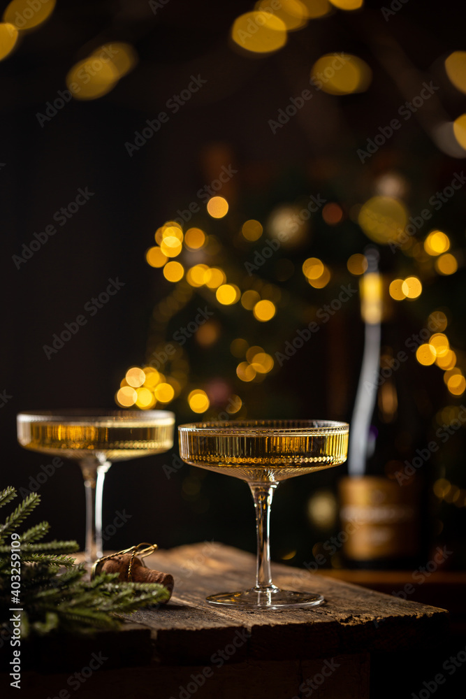 Two Glasses of champagne and bottle against fireworks and holiday lights, dark background