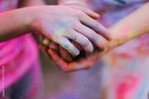 Hands with an engagement ring on bright background. Holi festival. Happy Valentine Day, Proposal, Love and Hippie lifestyle concept