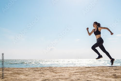 Fototapeta Naklejka Na Ścianę i Meble -  Asian healthy sport athlete girl running or jogging on beach in morning