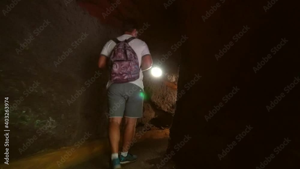 A young man on the path between tunnels through the canyon of Los Tilos natural park on the northeast coast of the island of La Palma, Canary Islands. Spain A young man on the path between tunnels through the canyon of Los Tilos natural park on the northeast coast of the island of La Palma, Canary Islands. Spain